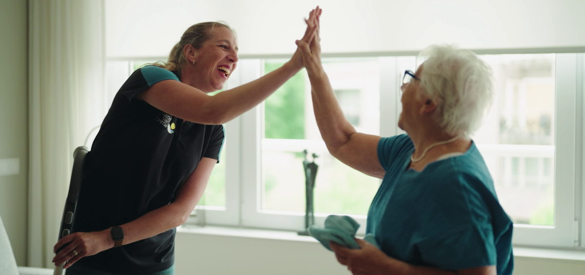 Medewerker huishouding geeft een cliënt een high five tijdens het schoonmaken