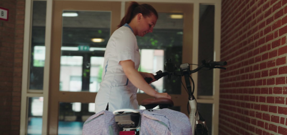 Verzorgende IG maakt haar fiets klaar voor de start van haar thuiszorgdienst