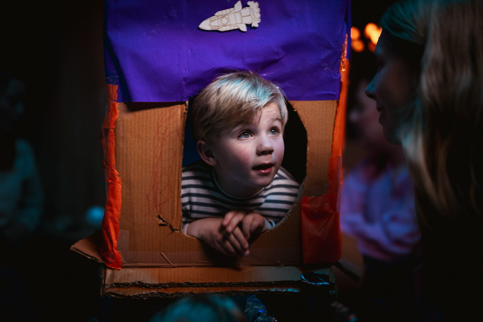 Jongen kijkt uit het raampje van een zelfgebouwde kartonnen raket op de kinderopvang