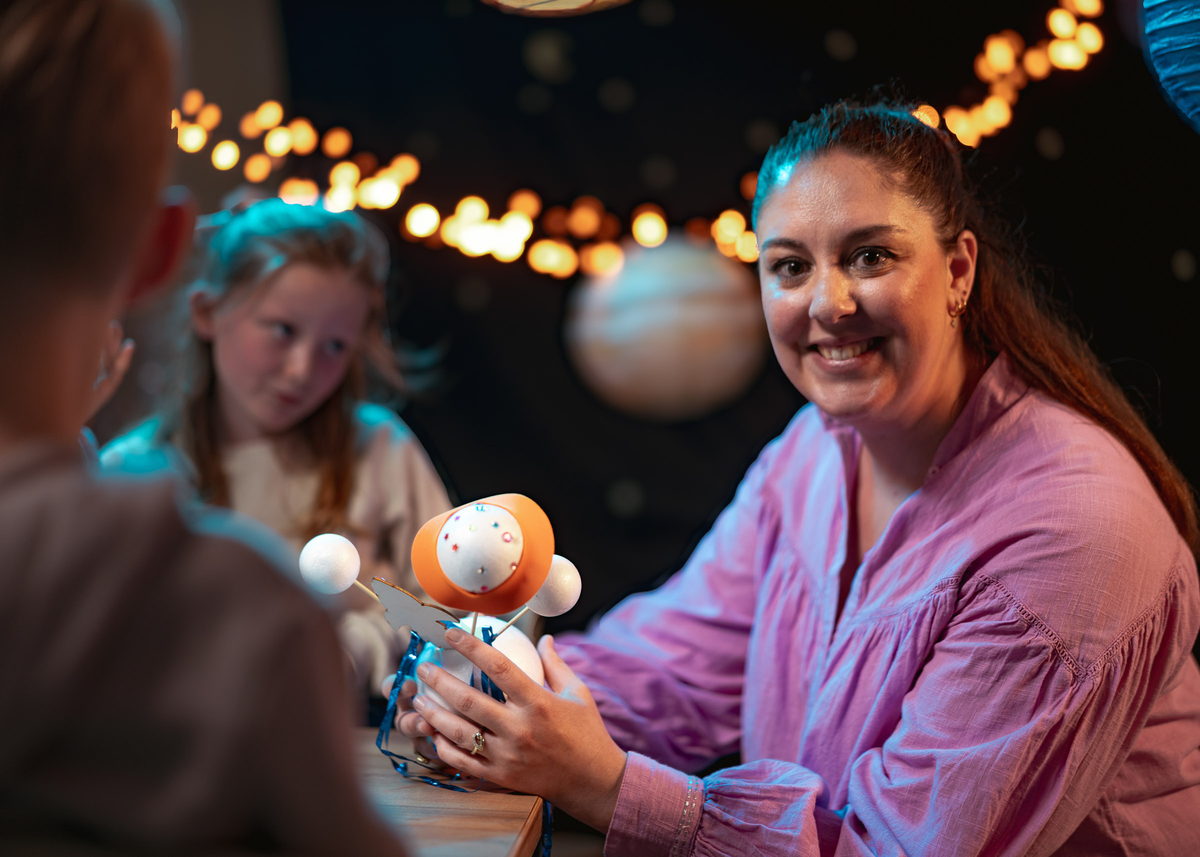 Pedagogisch professional van SKBNM knutselt met kinderen een astronaut van piepschuim